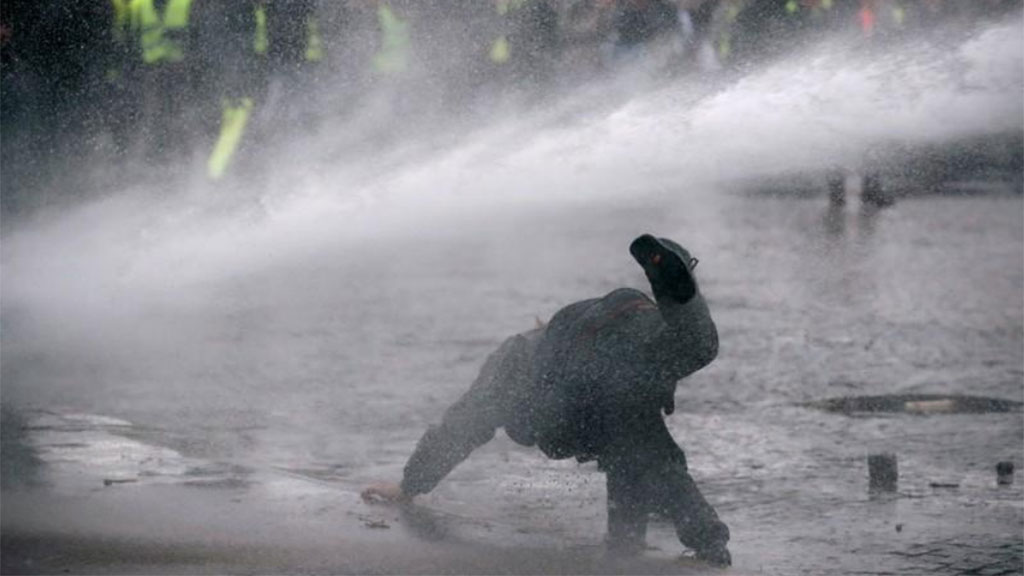 Manifestante é atingido por um jato de água gelada, no Centro de Paris, em pleno inverno