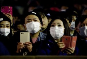 Pessoas com máscaras de proteção acompanham festival em templo em Okayama, no Japão