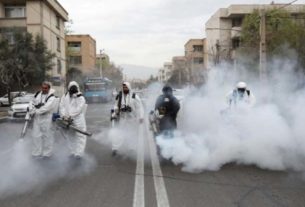 Bombeiros com roupa de proteção desinfectam ruas de Teerã