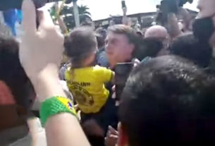 Bolsonaro, sem máscara, pega uma criança no colo, durante aglomeração em frente ao Palácio do Planalto