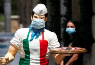 Estátua com máscara de proteção em frente a restaurante em Roma