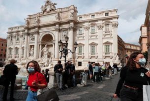 Pessoas usam máscaras de proteção perto da Fontana di Trevi, em Roma
