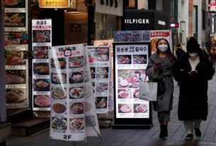 Mulheres caminham em distrito comercial vazio de Seul em meio à pandemia de covid-19