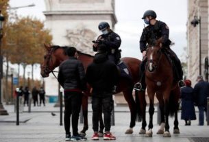 Policiais montados a cavalo e com máscaras de proteção checam identidade de pessoa na avenida Champs Elysee, em Paris