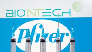 Seringas à frente de logos da Pfizer e da BioNTech